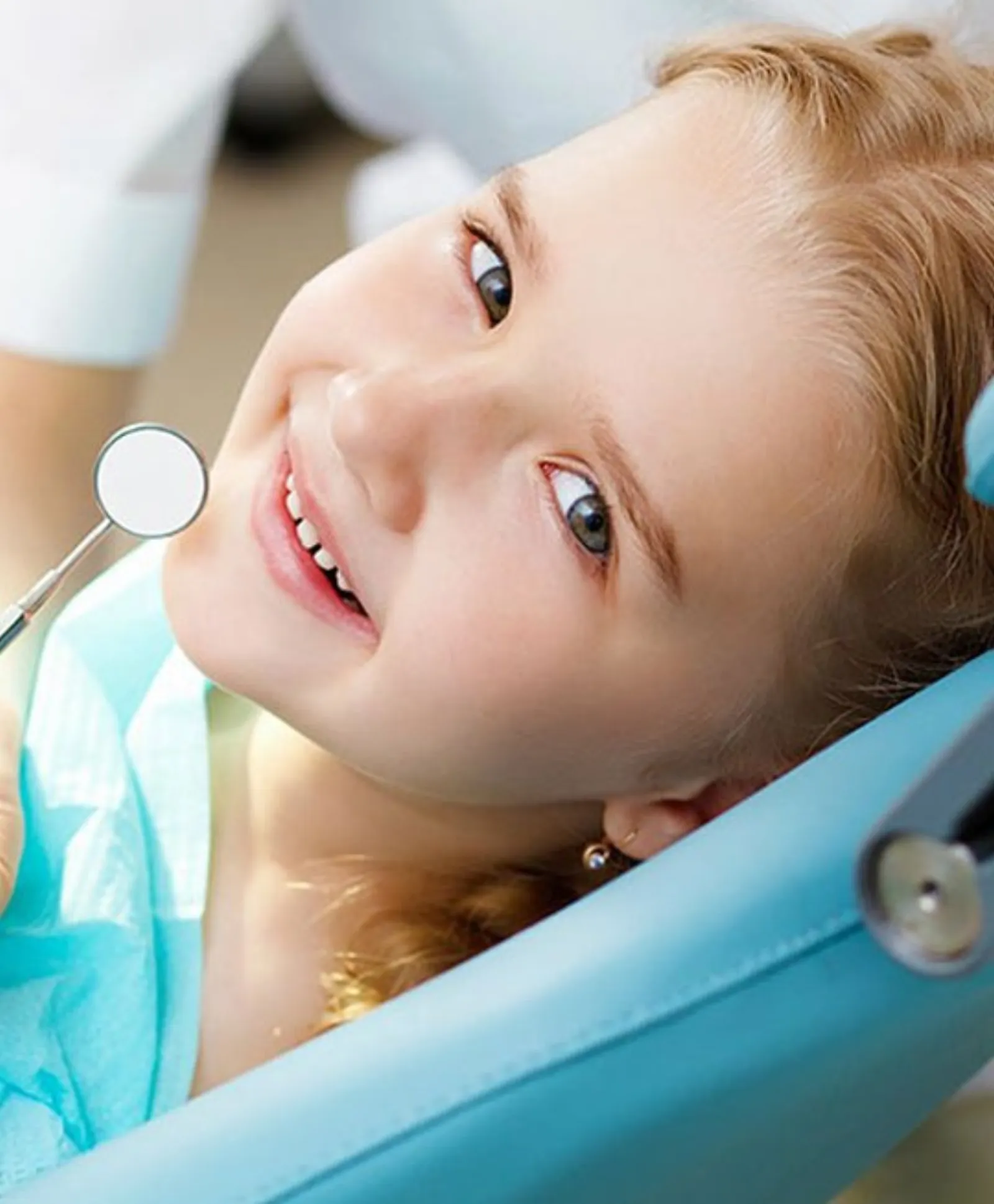 Niña sonriendo en el sillón dental
